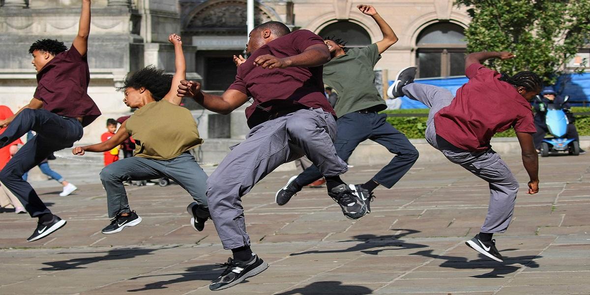 A group of people jumping in the air on Preston Flag Market as part of a dance routine.