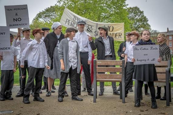 Children dressed as factory workers performing play in Winckley Square Gardens.