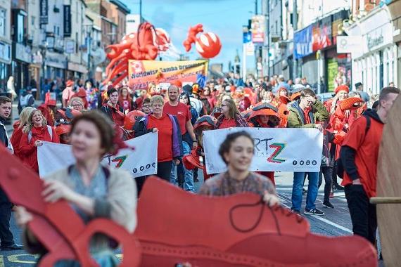 Parade taking place down Preston Friargate, with everyone dressed in red.