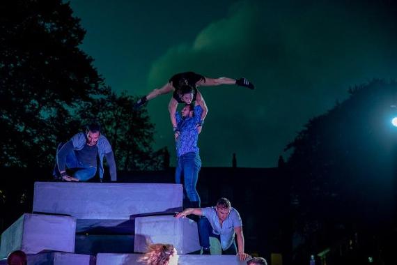 Performance of men and women taking place on giant blocks in Winckley Square at night.
