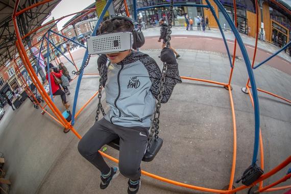 Boy wearing virtual reality headset whilst on a swing at Preston Markets.