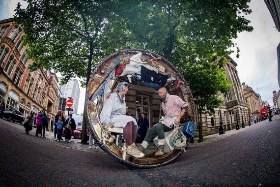 Man and woman performing on Preston streets inside a wheel.
