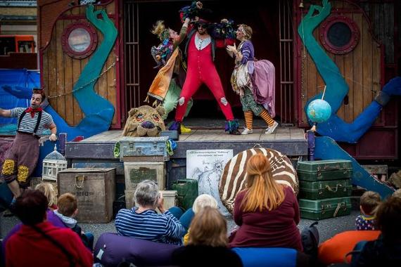 Actors performing a play, dressed in bohemian clothing, on a stage outdoors in Preston.