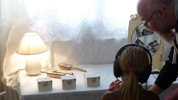 Young girl with headphones looking at a display of vintage items on a table.