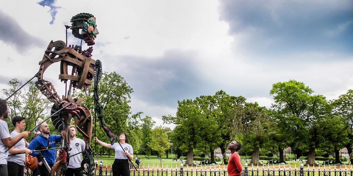 A metal sculpture with a little boy looking up at it